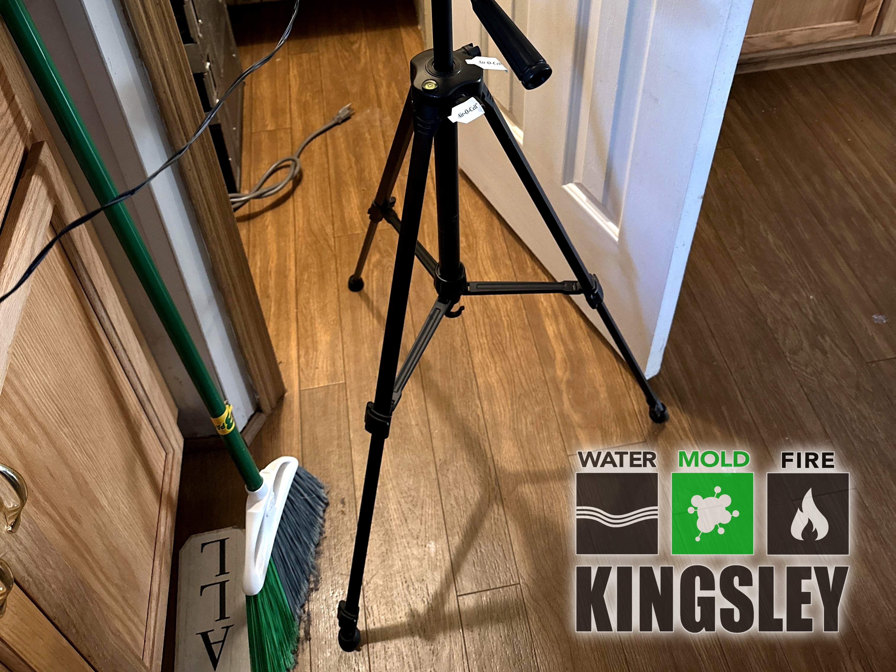Black air sampling pump on a tripod with cassette on wood-look flooring near a pantry during Kingsley mold inspection in Irmo, SC