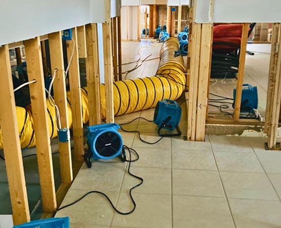 Blue drying fans and yellow ventilation tubes set up along a hallway